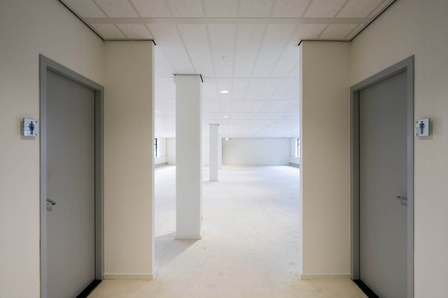 an empty room with two doors leading to bathrooms