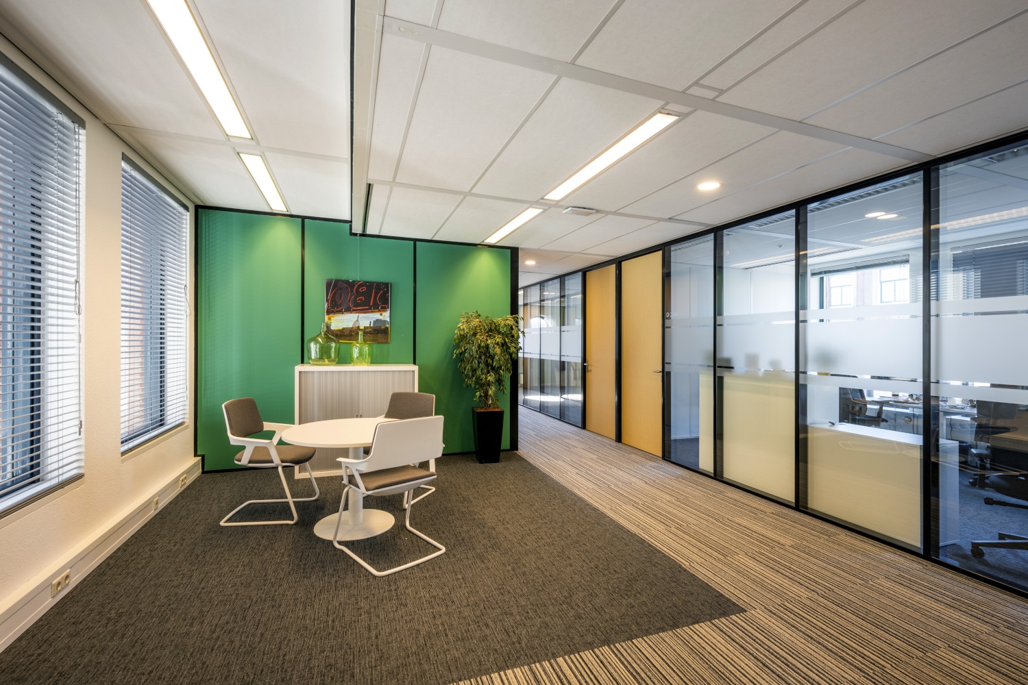 an office with a green wall and a white table and chairs