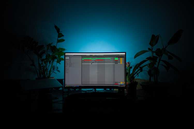 A computer monitor displaying a digital audio workstation interface in a dark room illuminated by blue light.