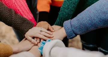 People standing in a circle with their hands stacked.