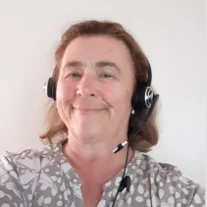 A close-up photo of Sue, smiling while wearing a phone headset.