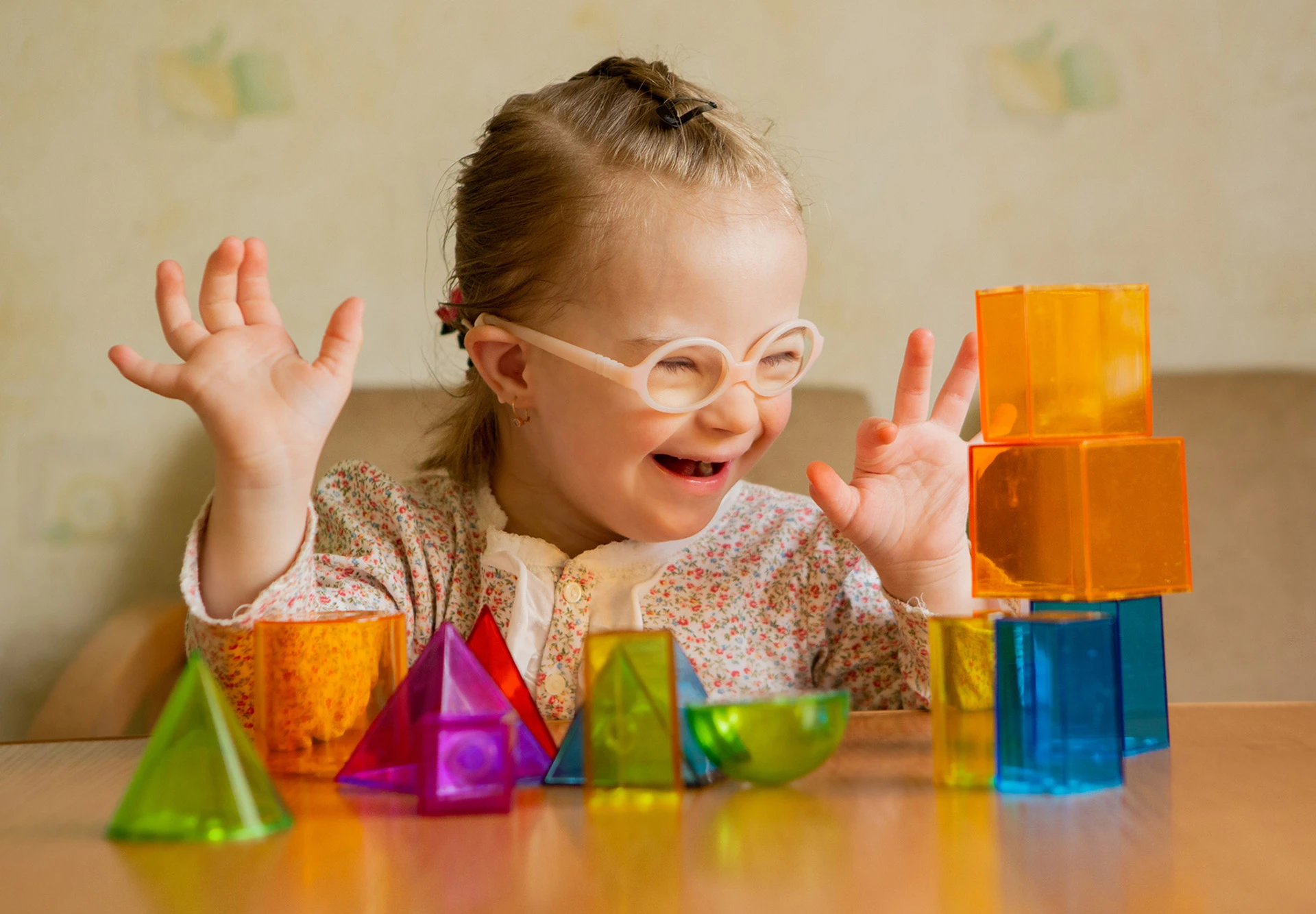 A little girl playing with colourful building blocks, looking happy.