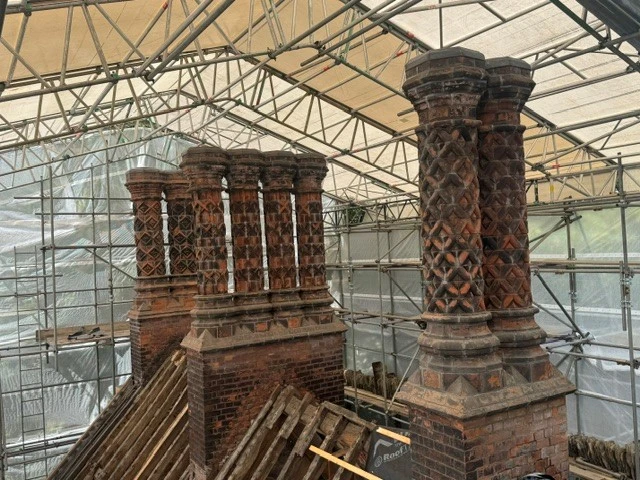 Ornate chimneys on the roof of Bramall Hall, surrounded by scaffolding.