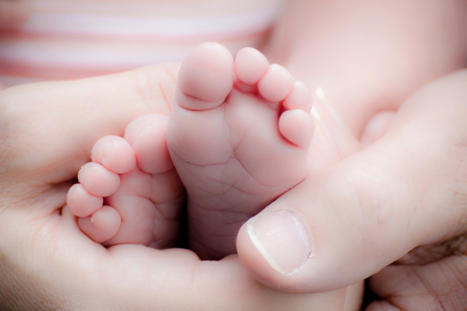 A baby's feet being held by an adult hand.
