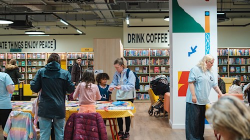 Group of people standing round a table in Stockroom taking parrt in crafts and activities.