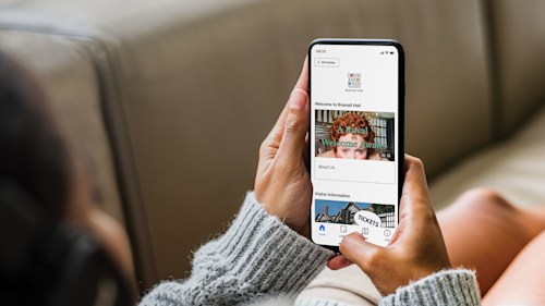 A person holding a smartphone with the screen displaying the Bloomberg Connects app.