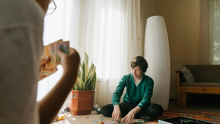 A man sitting in a chair and a boy sitting on the floor playing a card game.