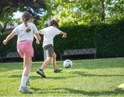 Two children playing football on a patch of grass.