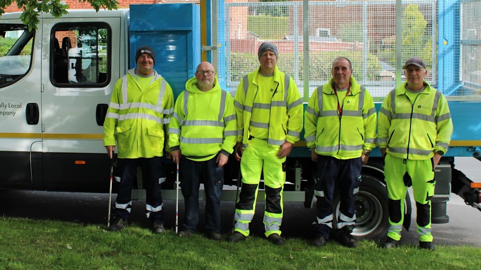 A group of TLC officers in hi-vis jackets standing with litter pickers outside a rubbish van. 