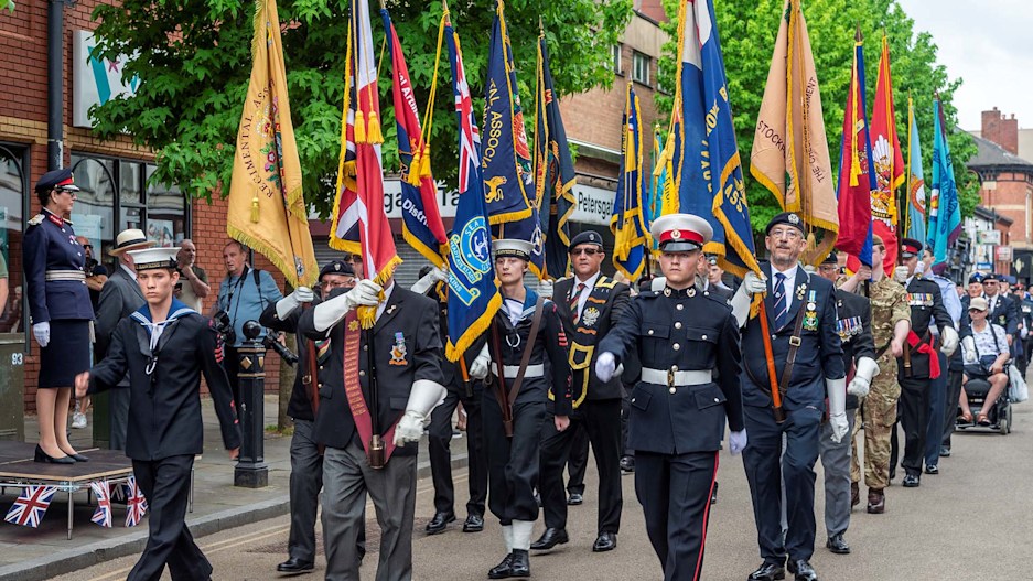 A uniformed military parade with flags, marching down a street in Stockport.