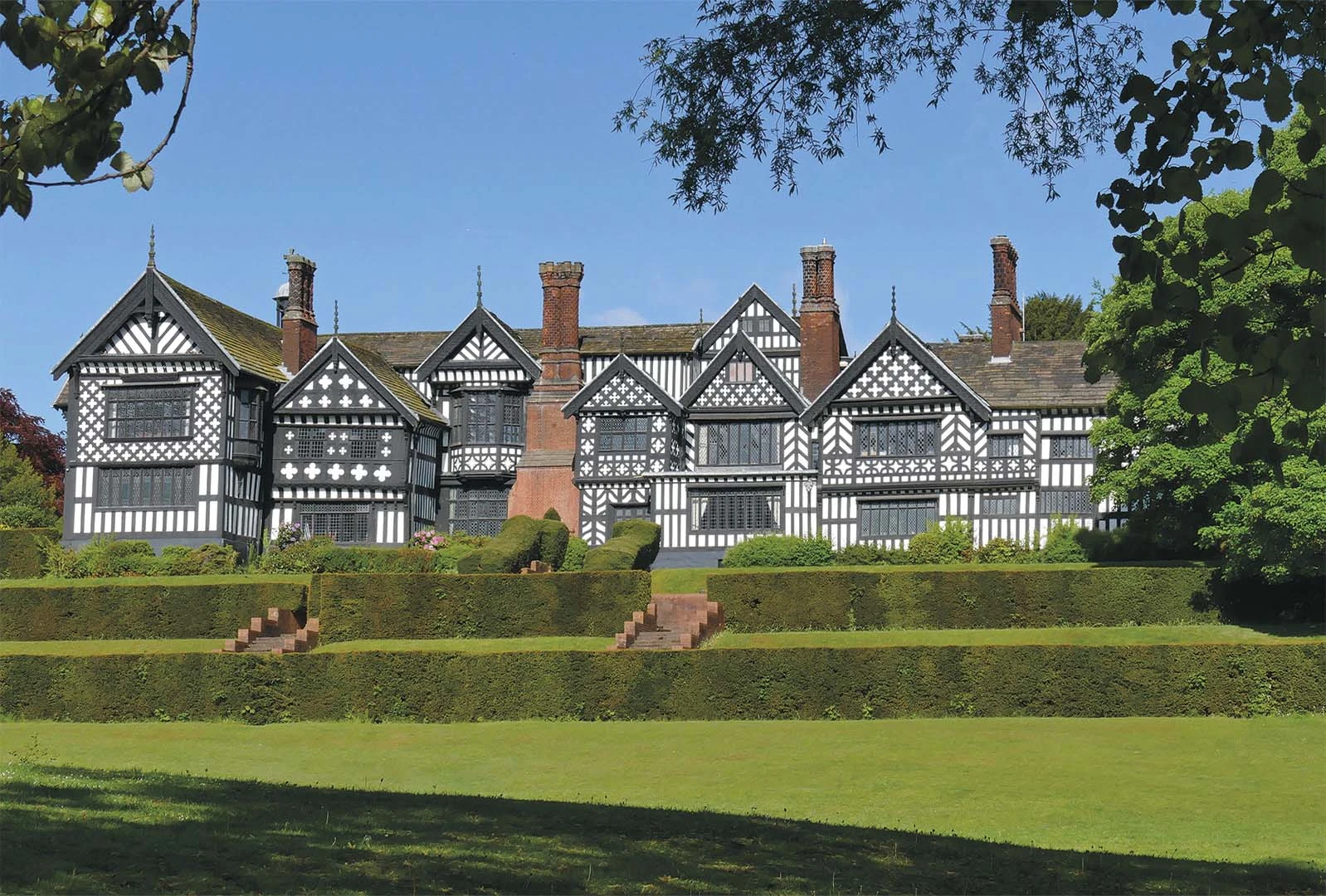Front of Bramall Hall, black and white tudor house in the sunshine