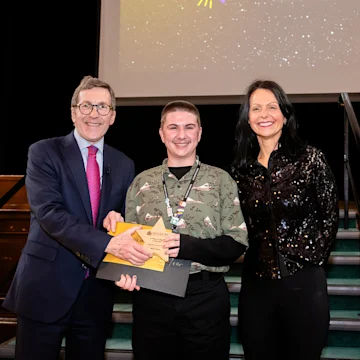 Aiden receiving an award, smiling at the camera.