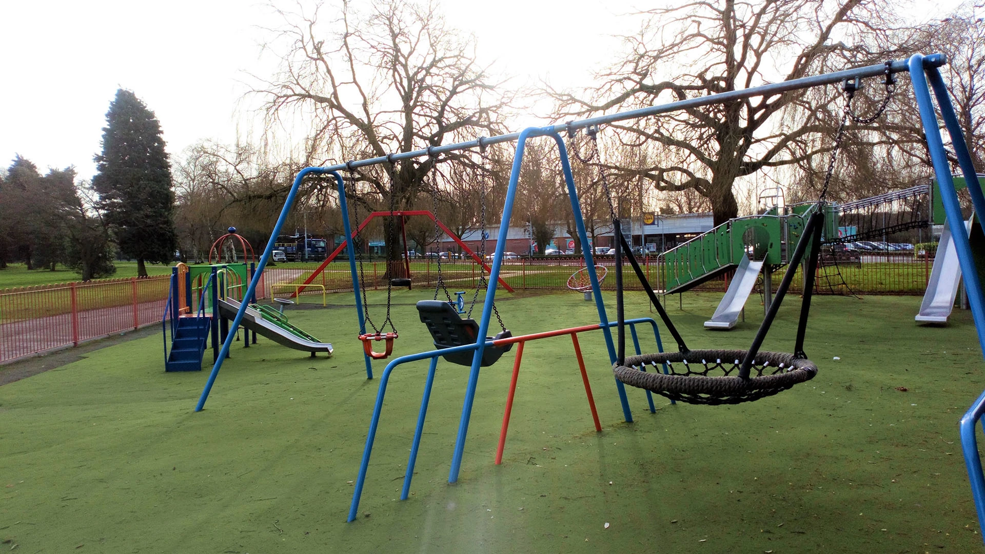 Play equipment in the park including slides and a variety of swing and accessible swings