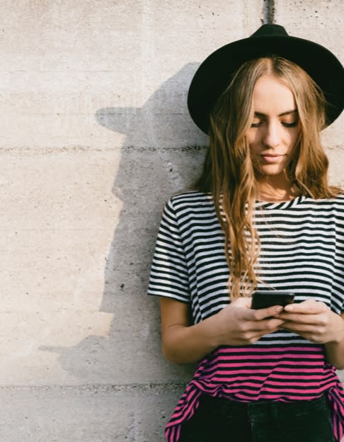 Tjej kollar på sin mobil med Comviq mobilabonnemang