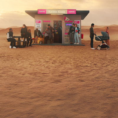 En liten kiosk med rosa skyltar står ensam i ett ökenlandskap med flera personer som samlas utanför.
