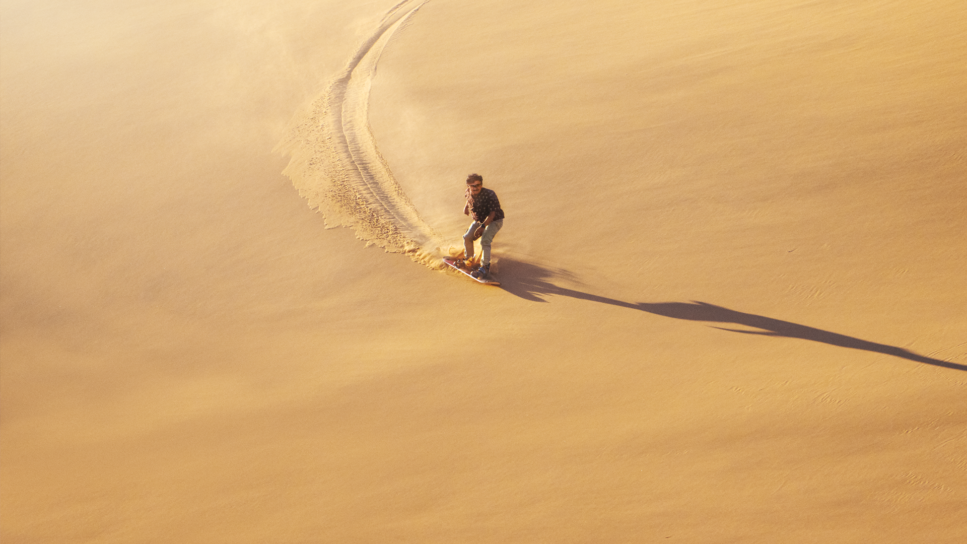 Karim surfar på sanddynorna i öknen.