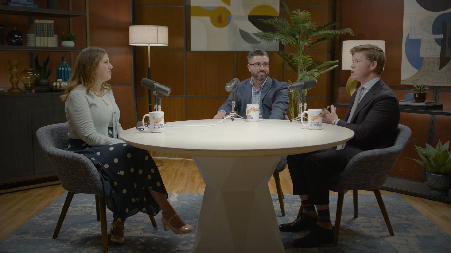 Three people sitting around a table with microphones