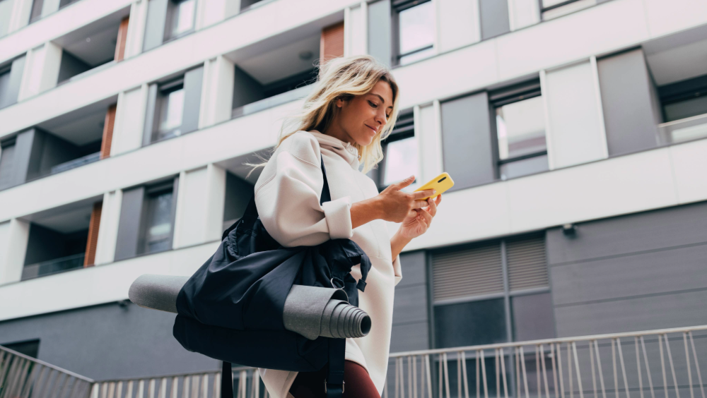 A woman walking by a building while on her phone