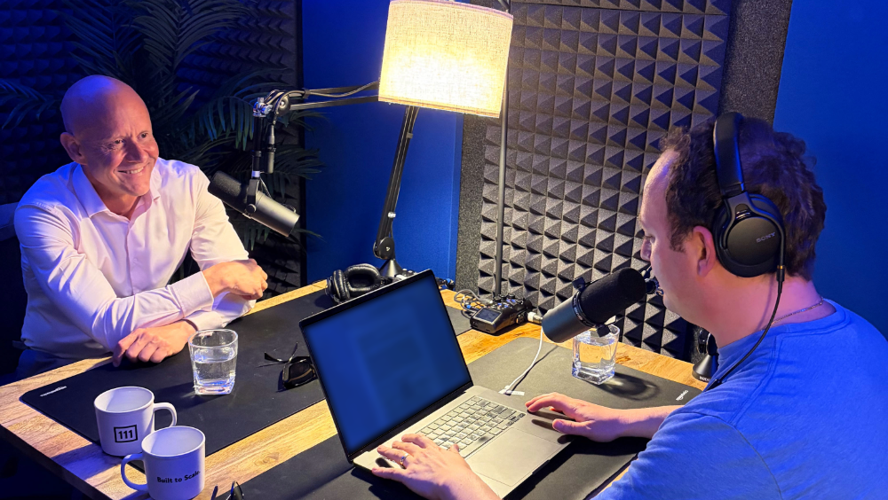 Two men sitting at a table with microphones