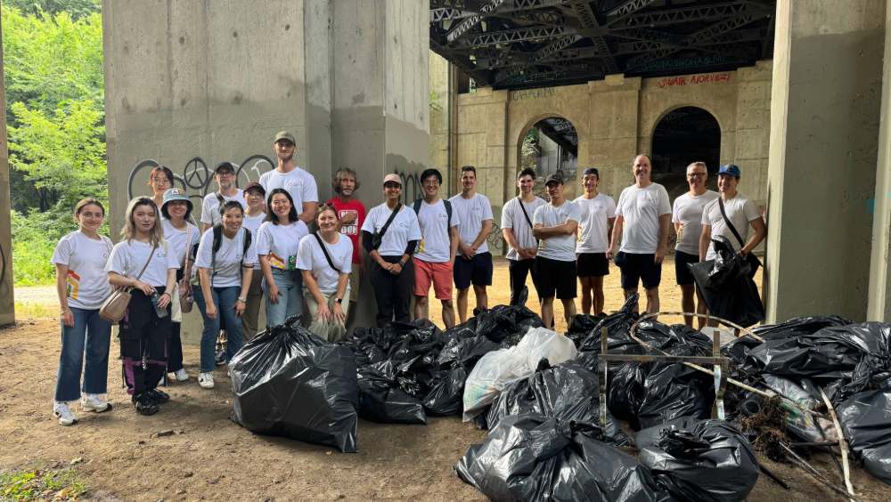A group of people standing in front of a pile of full garbage bags