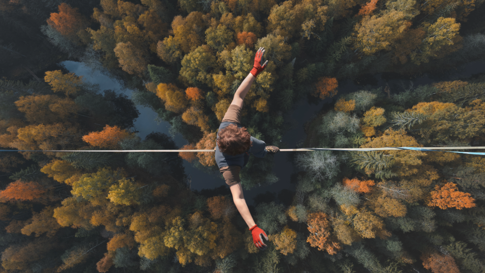 A man walking a tightrope over a forest