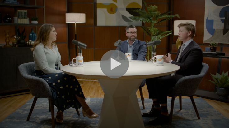 Three people sitting around a table with microphones