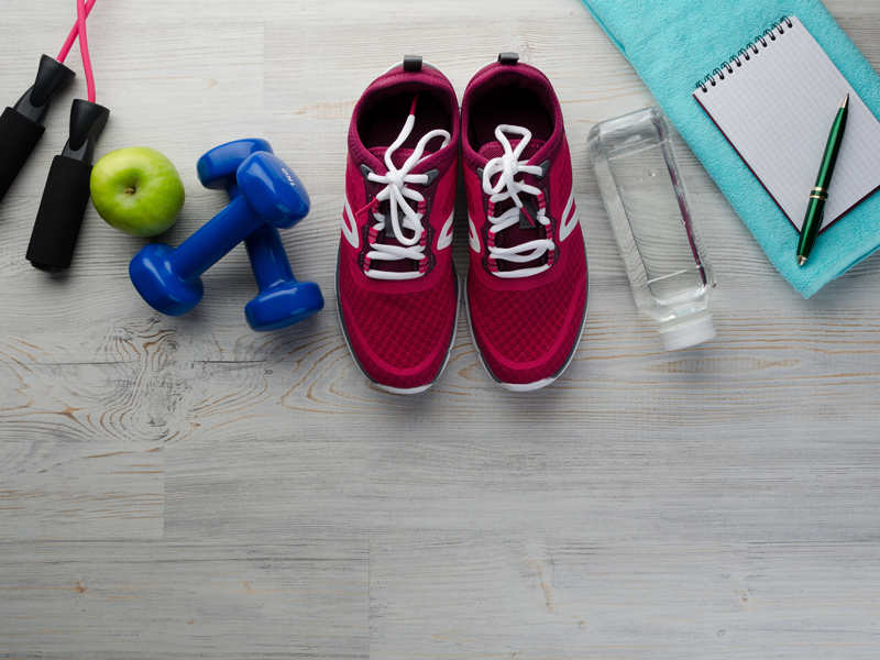 Image of gym equipment and red running shoes to represent healthy living