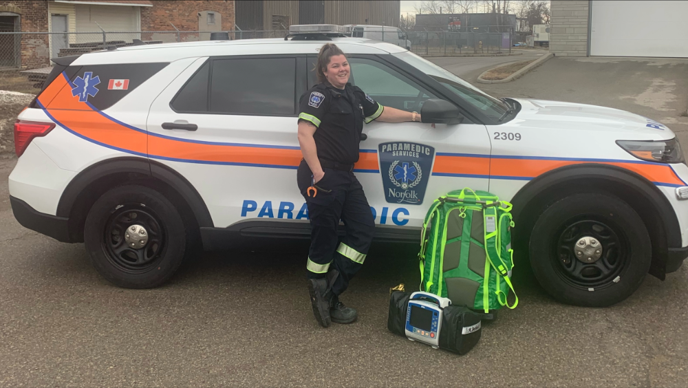 A female Norfolk county paramedic standing in front of her vehicle