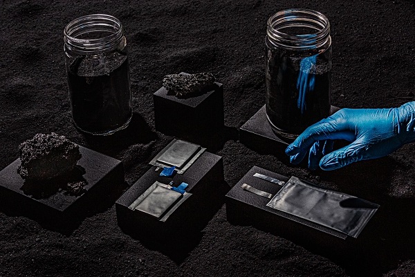 Image of hand reaching for lithium ion batteries in sand
