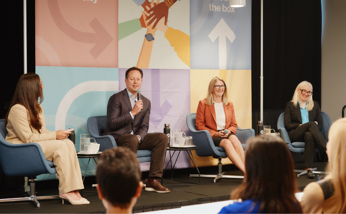 Four people speaking on a panel in front of an audience