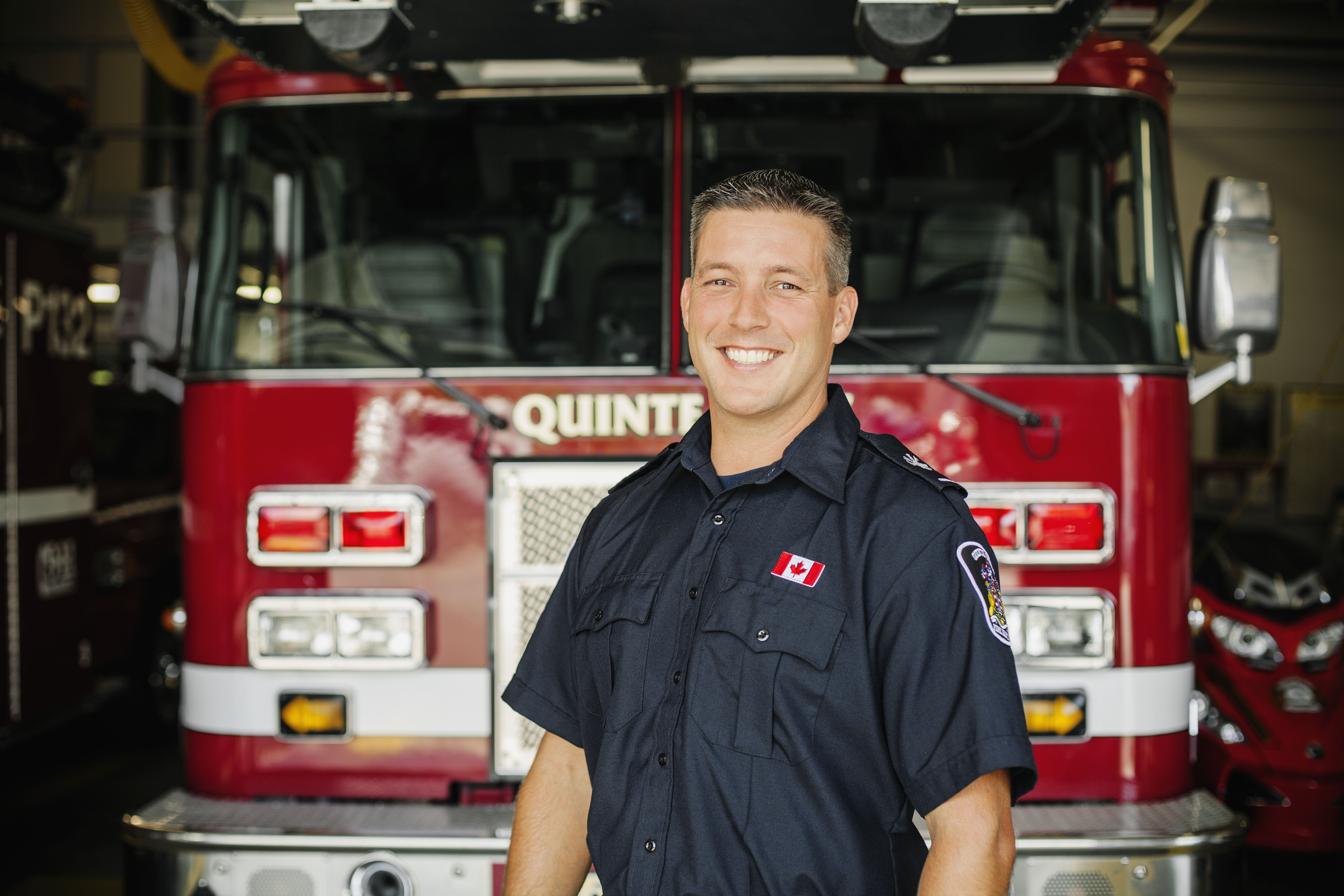 Off duty Fire fighter smiling in front of fire truck