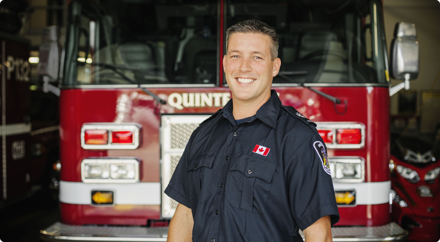 Off duty Fire fighter smiling in front of fire truck