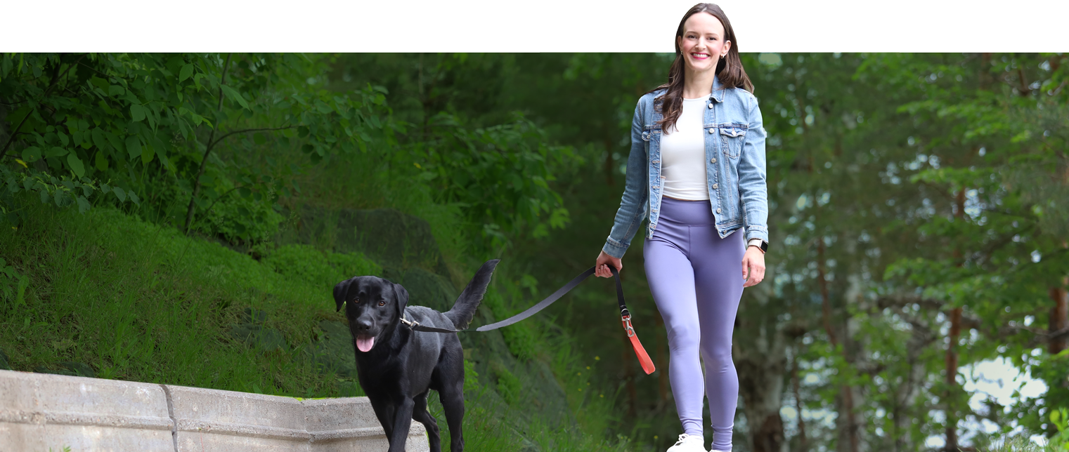 Female member walking her dog in a forest on a sunny day