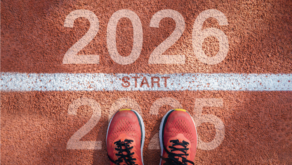 Running shoes at the starting line of a track that reads: 2026