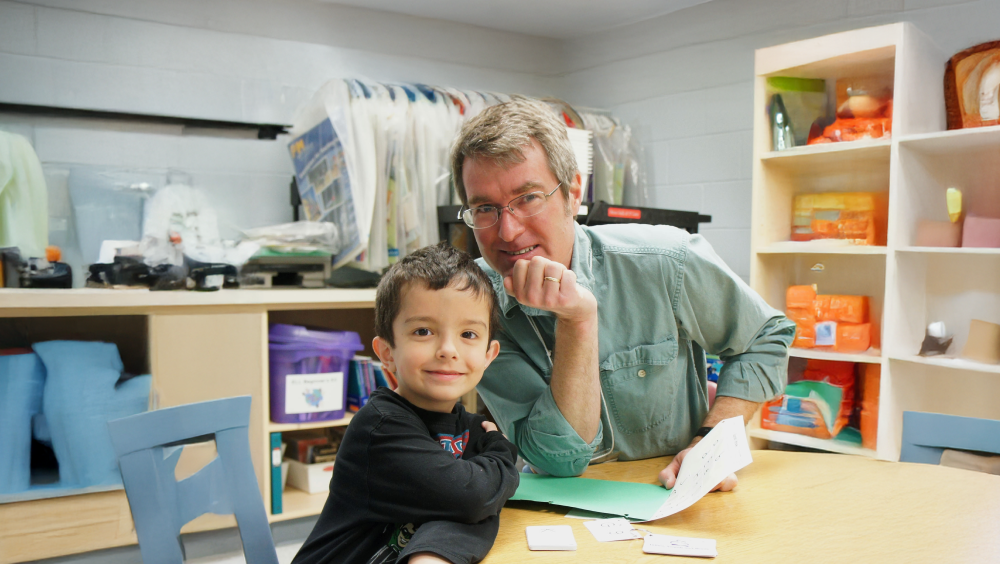 A young boy and his teacher sitting at a table