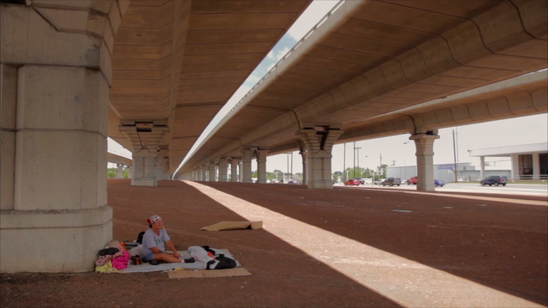 A woman sits with her belongings underneath an overpass in Austin.