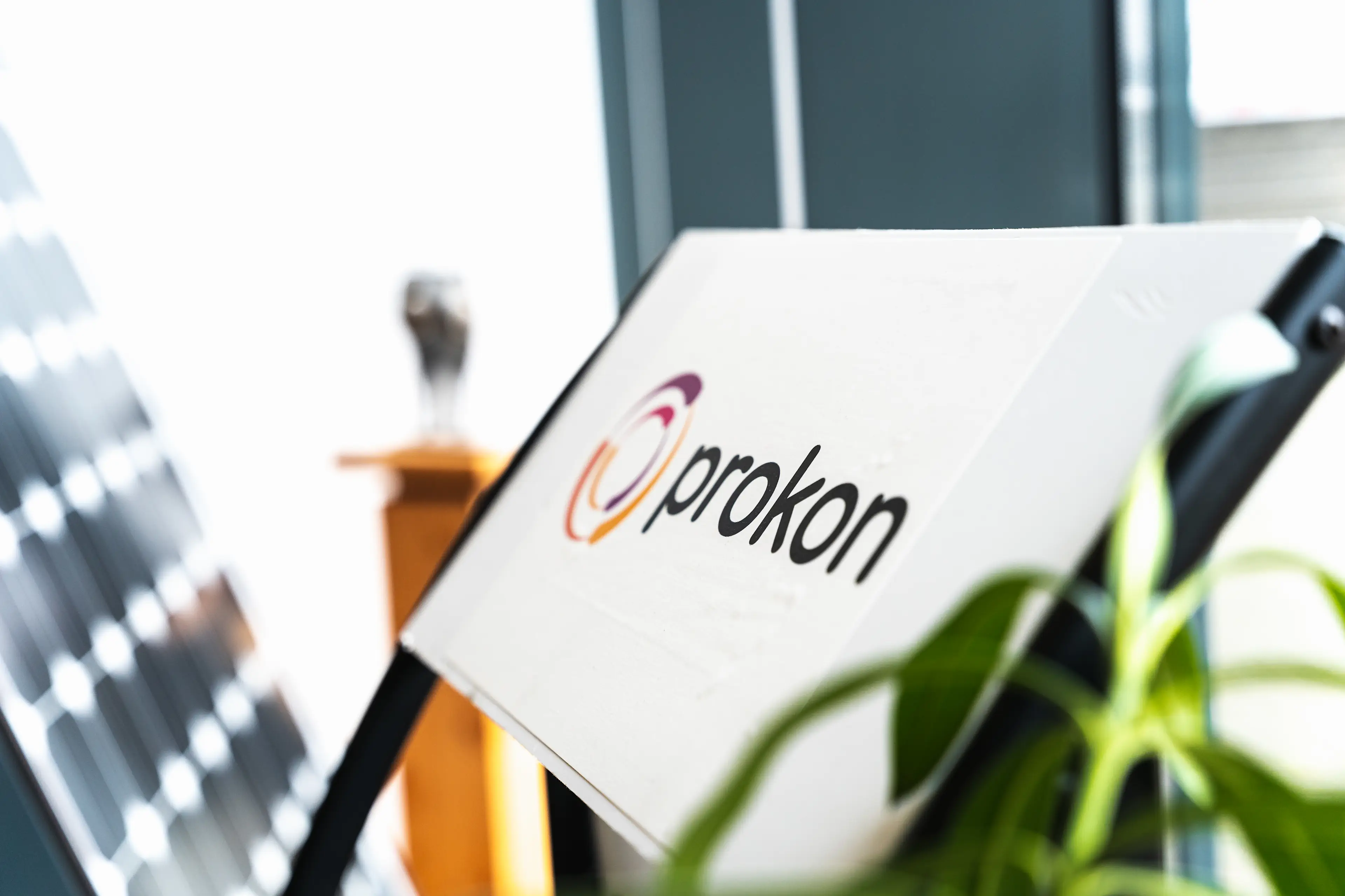 Prokon Logo auf einem Aufsteller mit weißem Hintergrund und schwarzer Schrift so wie farbigem Rotor