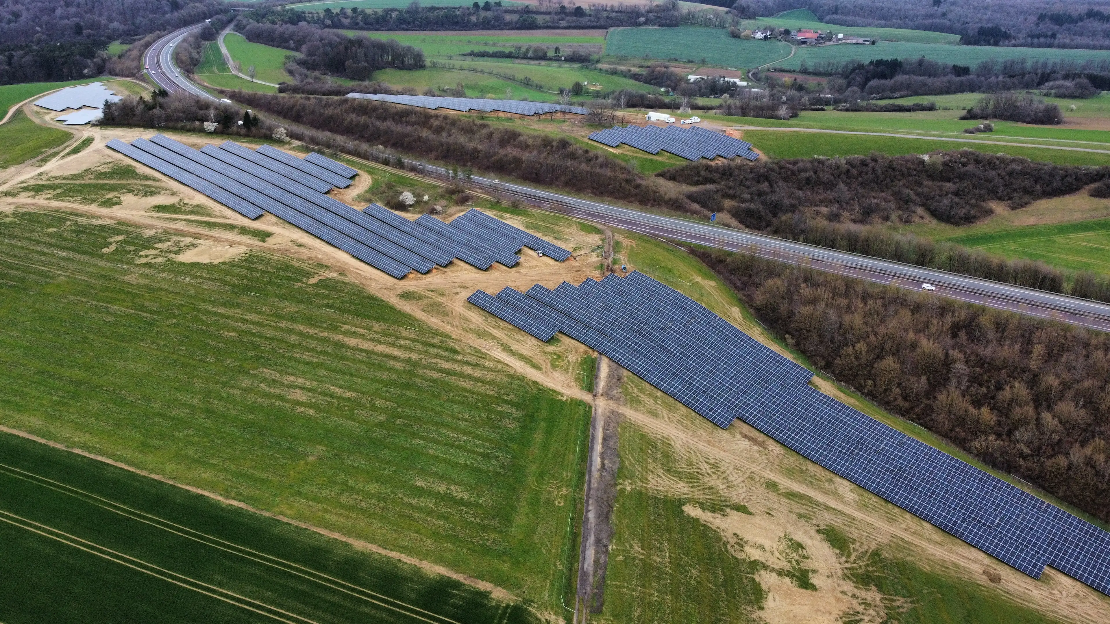 Auf dem Foto ist ein PV-Park mit einem Batteriespeicher auf freiem Feld dargestellt.