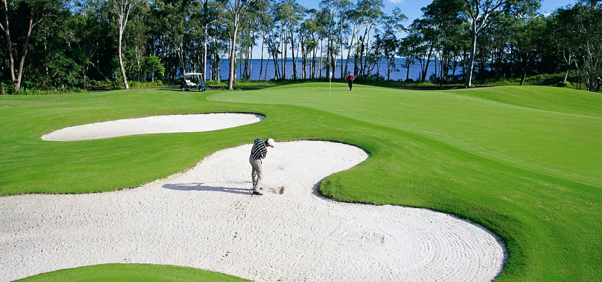 golf chipping from sand onto green