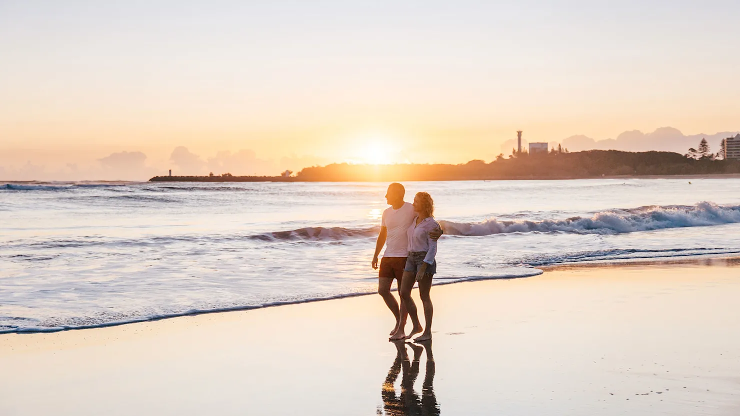 Couple walking at sunrise on Mooloolaba Beach