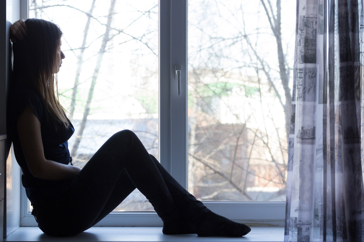 A woman looks out a window