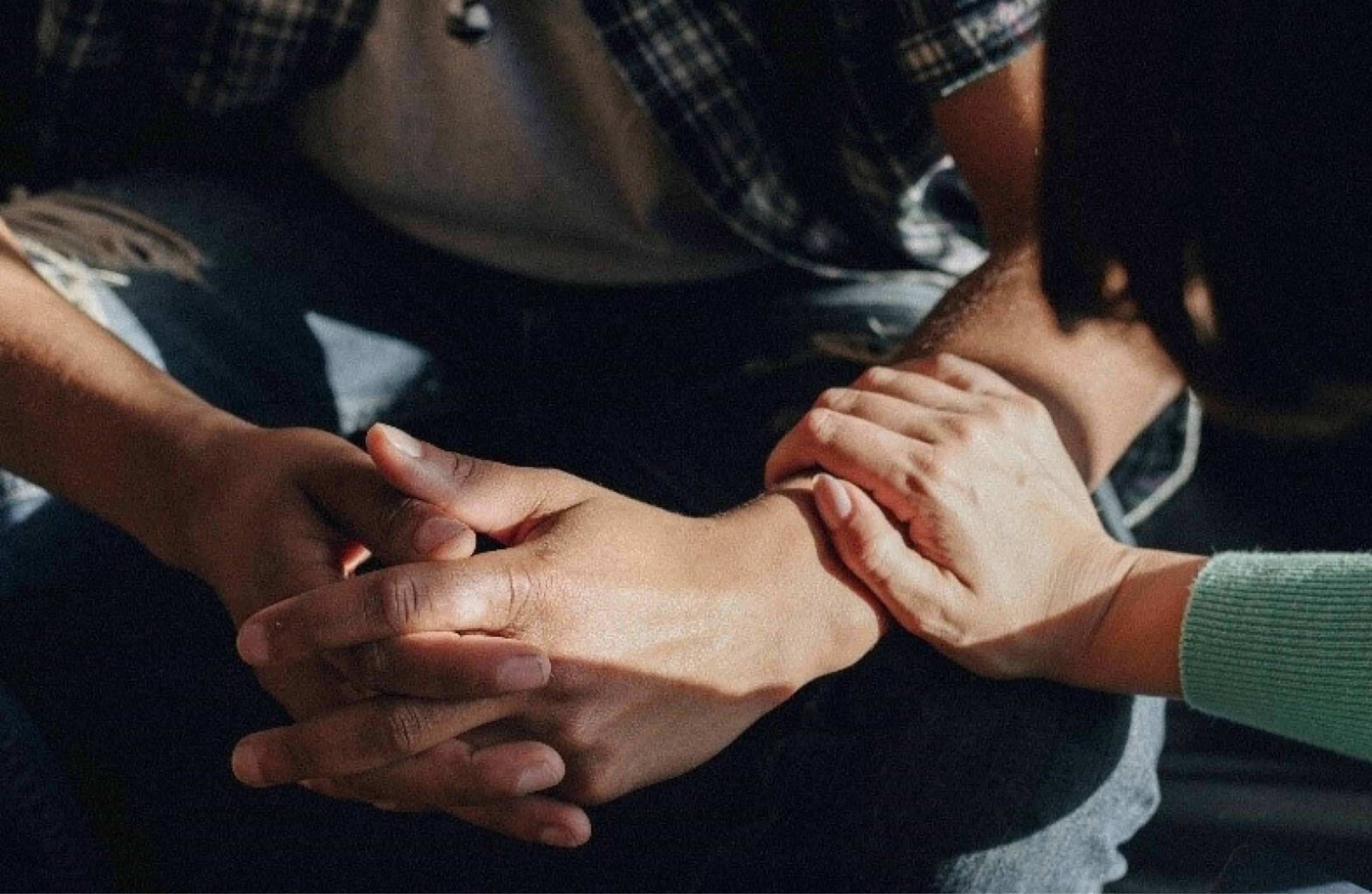 A closeup of two people, one supporting the other with hand outreached and resting on the young teens arm.