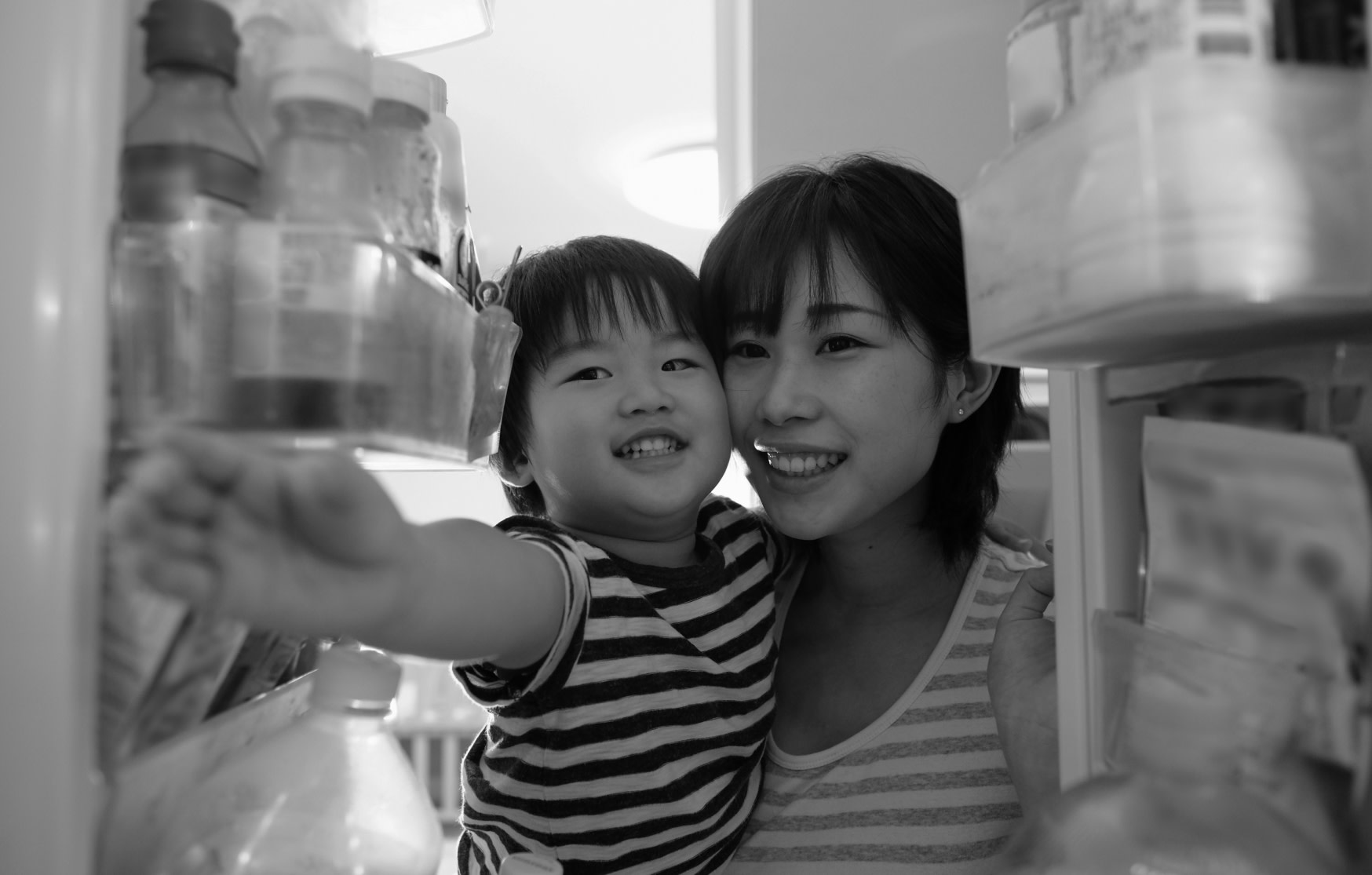 A mother and son reaching into the fridge.