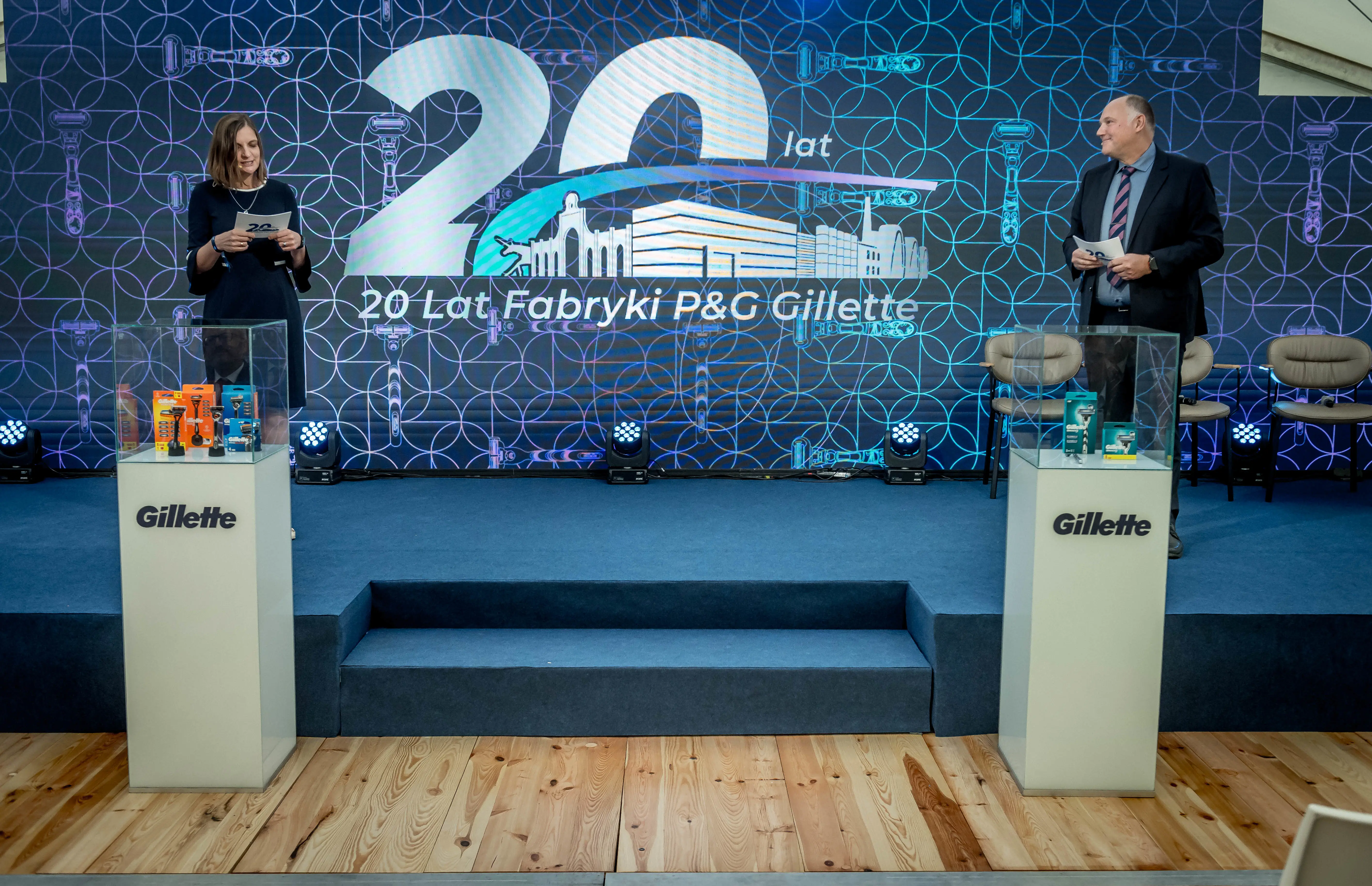 Zdjecie przedstawiające scenę oraz dwie osoby prowadzące wydarzenie z okazji 20lecia fabryki. 