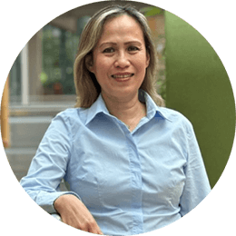 Azjatka o blond włosach sięgających do ramion, ubrana w jasnoniebieską koszulę z kołnierzykiem.