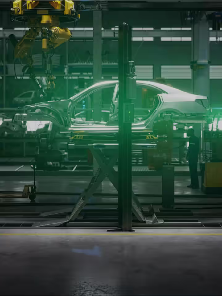 Side view of a car body on a production line in a car factory surrounded by various assembly machines