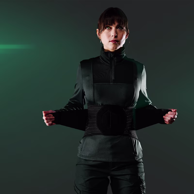 Front view of a woman in black clothing who is putting on the SUITX CX SOFT BACK on her lower back