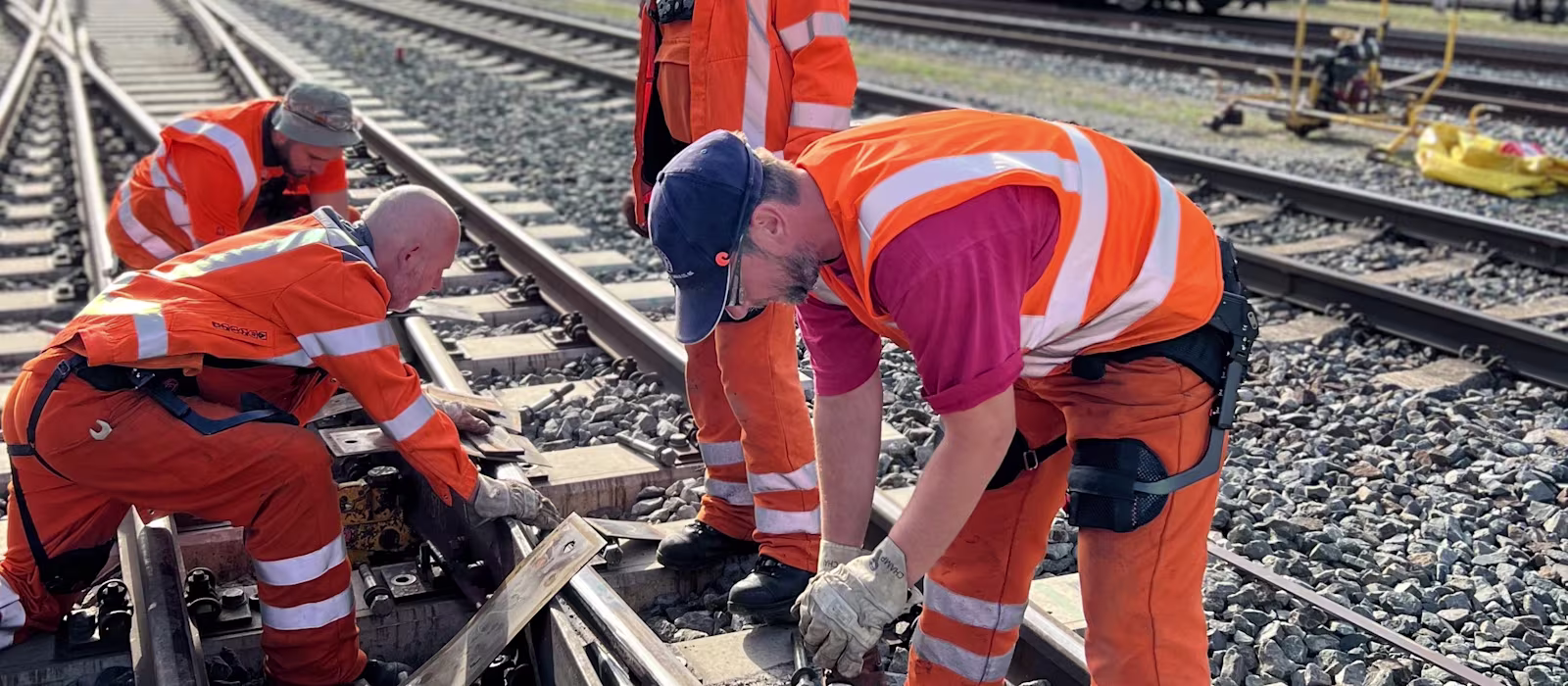 workers at train tracks in bending posture using back exoskeletons