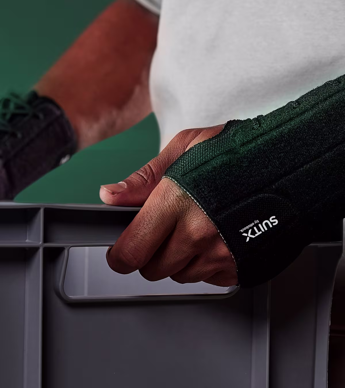 Torso view of a man carrying a box in front of his body and wearing the CX Soft Wrist.