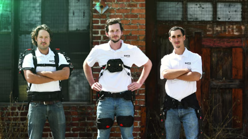 3 männliche Personen, das SUITX-Entwicklungsteam in Kalifornien, stehen draußen vor einem Gebäude und tragen Exoskelette
